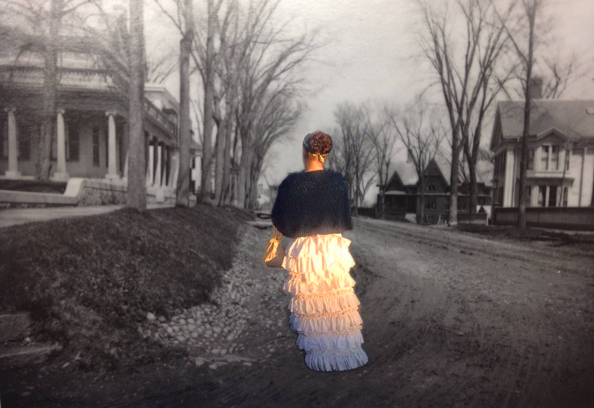 a woman in a bustle dress is pictured walking down a historic street